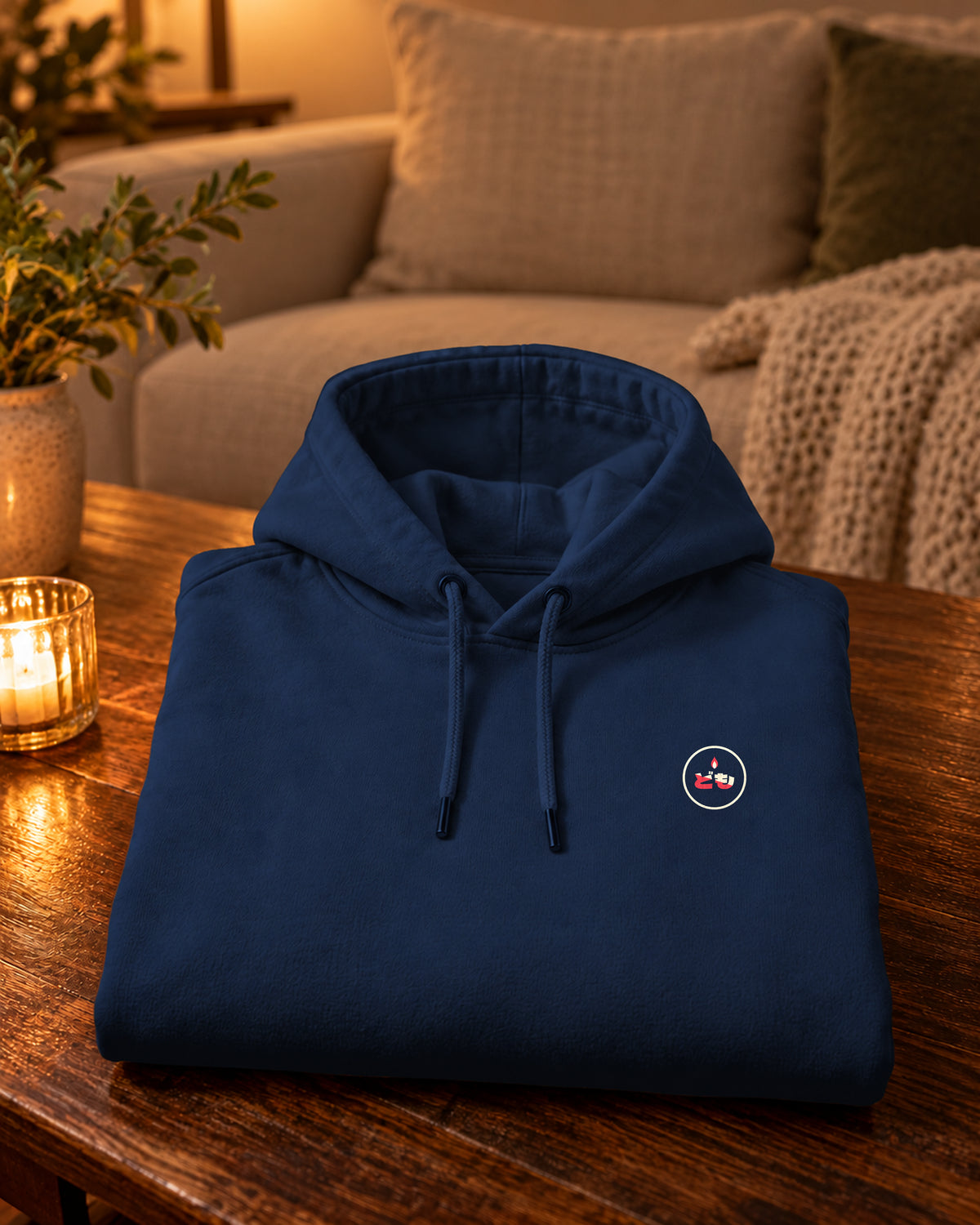 Nukumori Hoodie 温もり | Candle — Navy — gevouwen kledingstuk met origineel borstlogo op een tafel thuis bij kaarslicht