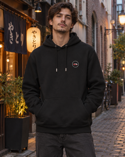 Nukumori Cruiser 2.0 350 GSM organic cotton fleece hoodie: RELAXED MEDIUM FIT, roomy chest and upper arms, shoulders gently relaxed, loose straight body and natural drape, comfortable streetwear, NOT slim or tight, NOT extreme oversized — Origin Dark — front logo on model