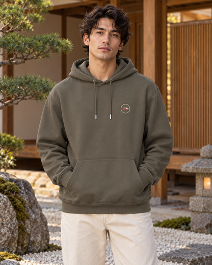 Nukumori Cruiser 2.0 350 GSM organic cotton fleece hoodie: RELAXED MEDIUM FIT, roomy chest and upper arms, shoulders gently relaxed, loose straight body and natural drape, comfortable streetwear, NOT slim or tight, NOT extreme oversized — Zen Dark — front logo on model