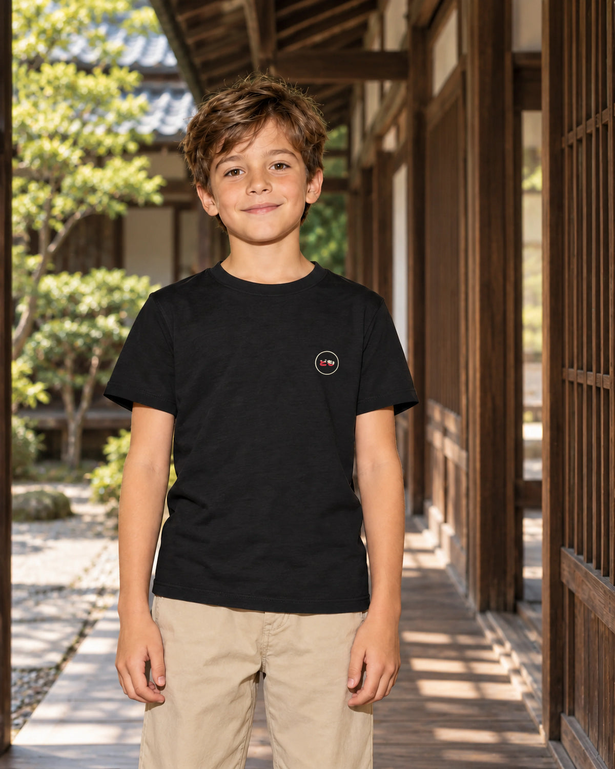 Wakaba Kids Tee 若葉 | Ink — front view showing the Domo chest logo in a Japanese wooden courtyard