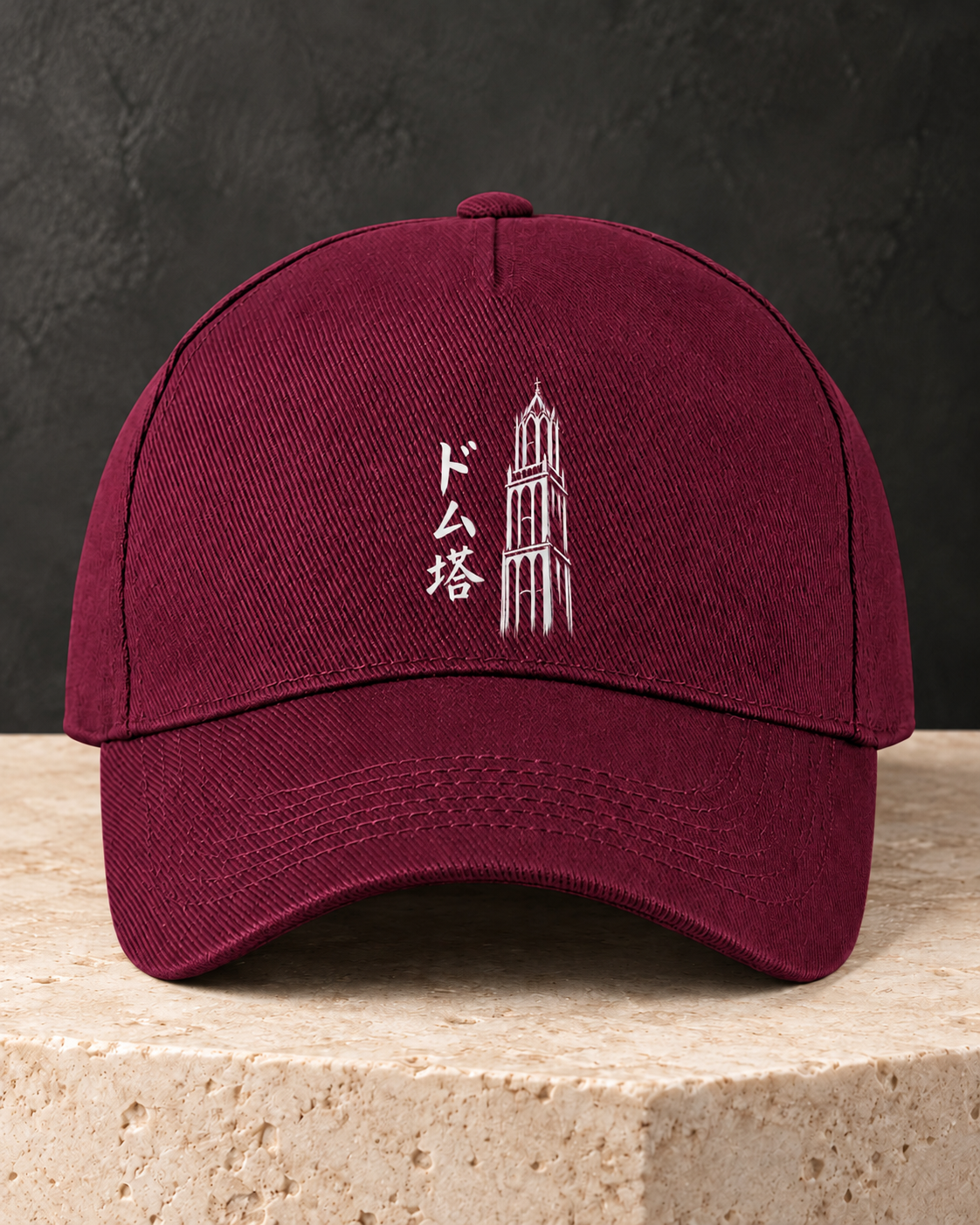 Kage Cap 影 | Burgundy — vooraanzicht op een lichte stenen sokkel met wit Ink-ontwerp